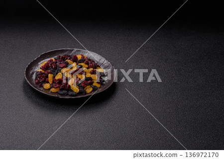 Dried cranberries, yellow and black sweet raisins as ingredients for a breakfast. Raisins and cranberries Dried cranberries, yellow and black sweet raisins as ingredients for a breakfast. Raisins and cranberries 136972170