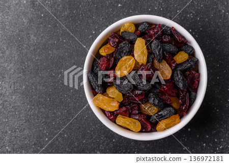 Dried cranberries, yellow and black sweet raisins as ingredients for a breakfast. Raisins and cranberries Dried cranberries, yellow and black sweet raisins as ingredients for a breakfast. Raisins and cranberries 136972181