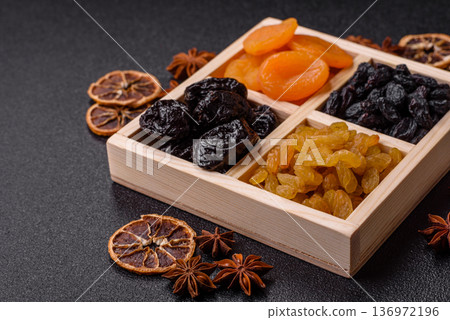A variety of dried fruits, apricots, prunes, cranberries, raisins, figs, and dates for a healthy breakfast. A dried fruit mix 136972196