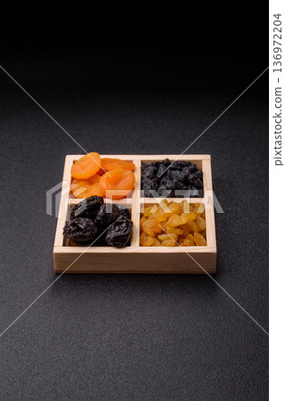 A variety of dried fruits, apricots, prunes, cranberries, raisins, figs, and dates for a healthy breakfast. A dried fruit mix 136972204