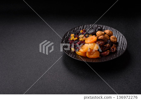 A variety of dried fruits, apricots, prunes, cranberries, raisins, figs, and dates for a healthy breakfast. A dried fruit mix 136972276
