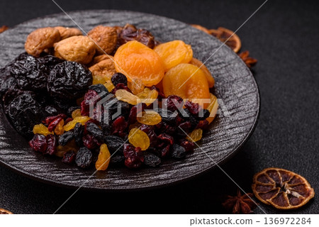 A variety of dried fruits, apricots, prunes, cranberries, raisins, figs, and dates for a healthy breakfast. A dried fruit mix 136972284