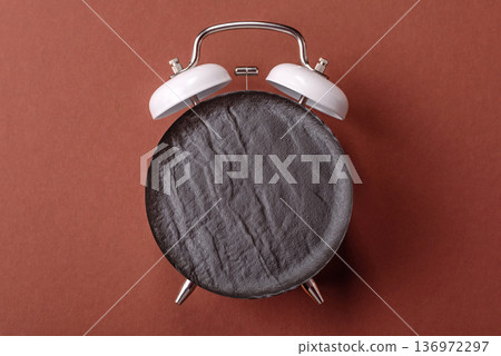 Vintage alarm clock on brown surface as a conceptual background for deadlines for tasks 136972297