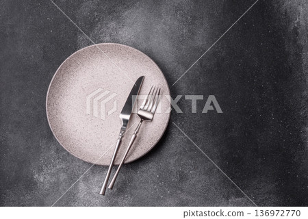 An empty round ceramic plate, knife, and fork as a dining table setting. An empty plate An empty round ceramic plate, knife, and fork as a dining table setting. An empty plate 136972770