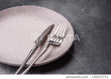 An empty round ceramic plate, knife, and fork as a dining table setting. An empty plate An empty round ceramic plate, knife, and fork as a dining table setting. An empty plate 136972772