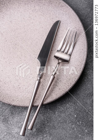 An empty round ceramic plate, knife, and fork as a dining table setting. An empty plate An empty round ceramic plate, knife, and fork as a dining table setting. An empty plate 136972773
