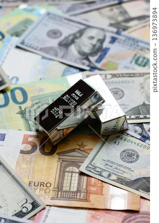 A silver bar, white metal against a backdrop of money, as a concept for the sales. A silver bar A silver bar, white metal against a backdrop of money, as a concept for the sales. A silver bar 136973894