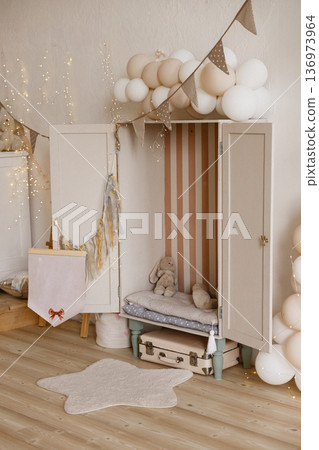Cozy decorated corner with white wardrobe, pastel balloons, bunting and star rug 136973964