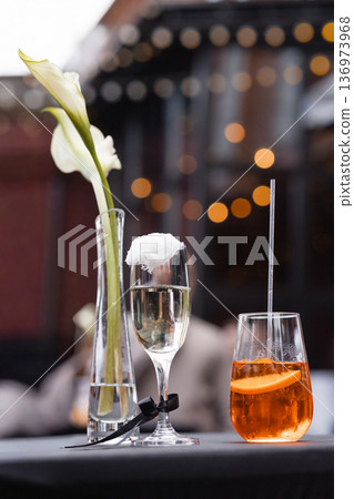 Elegant cocktail arrangement with champagne flute and rocks glass on wooden table with bokeh lights 136973968