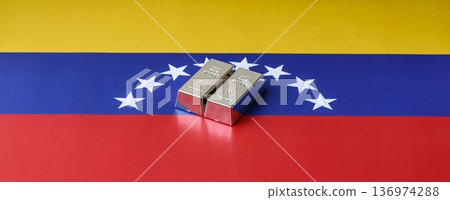 A silver bar, white metal against a flag of venezuela, as a concept for the sales. A silver bar A silver bar, white metal against a flag of venezuela, as a concept for the sales. A silver bar 136974288