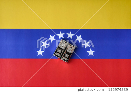 A silver bar, white metal against a flag of venezuela, as a concept for the sales. A silver bar 136974289