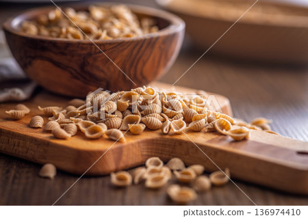 Wholegrain conchiglie pasta on wooden table. Wholegrain conchiglie pasta on wooden table. 136974410
