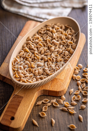 Wholegrain conchiglie pasta in bowl on wooden table. 136974411