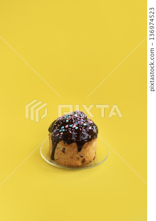 Easter cake with chocolate topping on light yellow background, bright and cheerful seasonal dessert styling 136974523