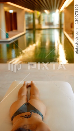 Female lying back in swimwear reflecting serene poolside atmosphere Female lying back in swimwear reflecting serene poolside atmosphere 136975196