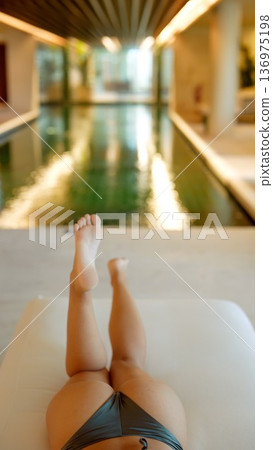 Serene posture with feet resting at shimmering indoor pool edge 136975198