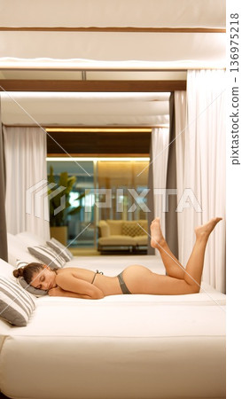 Chic woman relaxing with lifted leg under gentle lighting Chic woman relaxing with lifted leg under gentle lighting 136975218