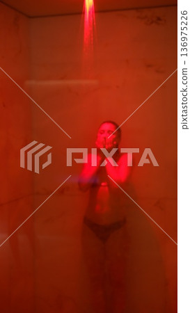 Tranquil Asian female with cheerful expression under soft red glow Tranquil Asian female with cheerful expression under soft red glow 136975226