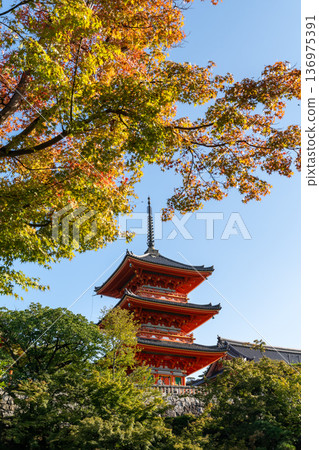 Red Japanese pagoda temple framed by autumn leaves in Kyoto, Japan Red Japanese pagoda temple framed by autumn leaves in Kyoto, Japan 136975391