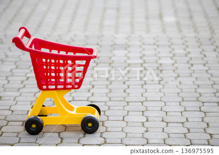Bright plastic colorful shopping cart toy outdoors on sunny summer day. Bright plastic colorful shopping cart toy outdoors on sunny summer day. 136975595