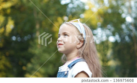 Portrait of happy cute child girl in summer outdoors. 136975608