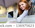 Young woman with red hair driving a car. 136975623
