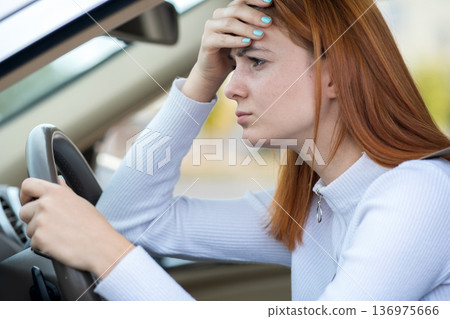 Sad tired yound woman driver sitting behind the car steering wheel in traffic jam. 136975666