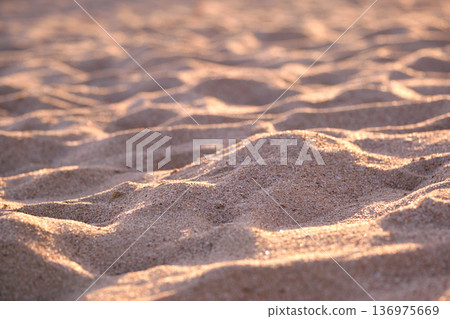 Close up of clean yellow sand surface covering seaside beach illuminated with evening light. Travel and vacations concept Close up of clean yellow sand surface covering seaside beach illuminated with evening light. Travel and vacations concept 136975669