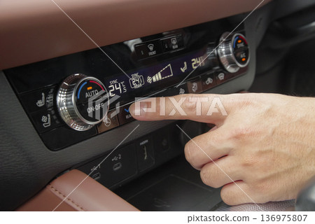 A man adjusting the temperature of his car's air conditioner A man adjusting the temperature of his car's air conditioner 136975807