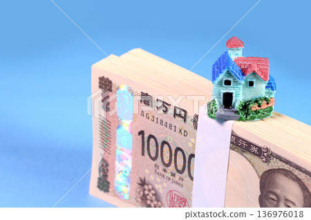A stack of new banknotes and a miniature house (image of real estate and mortgage) A stack of new banknotes and a miniature house (image of real estate and mortgage) 136976018