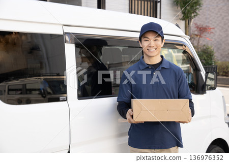 Smiling courier man delivering a package Smiling courier man delivering a package 136976352
