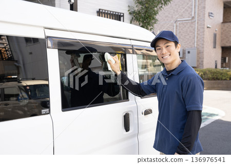 一名男子正在擦拭一輛洗過的車。 一名男子正在擦拭一輛洗過的車。 136976541