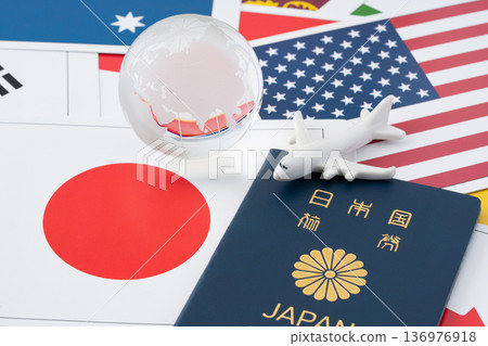 A blue Japanese passport with a miniature airplane and globe against a backdrop of many flag cards 136976918