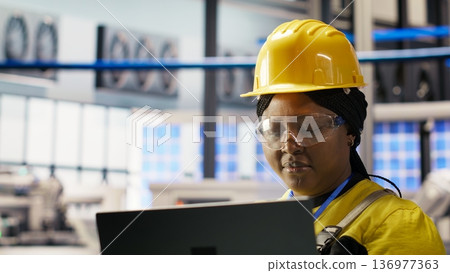 Specialist using laptop to conduct routine inspections in industry 4.0 plant producing renewable energy. Technician in photovoltaics smart factory testing equipment using notebook, camera B Specialist using laptop to conduct routine inspections in industry 4.0 plant producing renewable energy. Technician in photovoltaics smart factory testing equipment using notebook, camera B 136977363