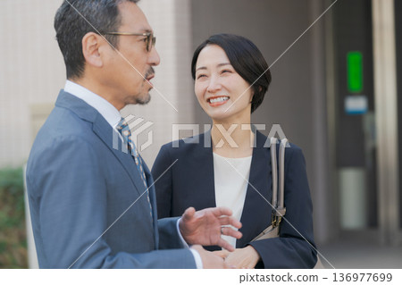 Men and women in suits walking and chatting Men and women in suits walking and chatting 136977699
