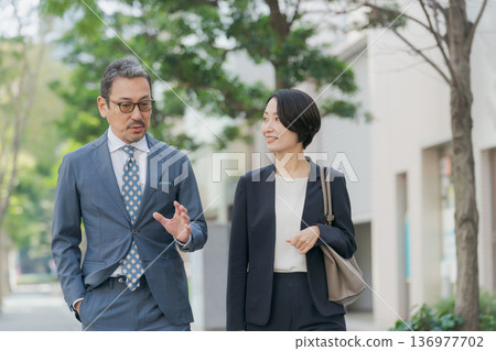 身著西裝的男女邊走邊聊 身著西裝的男女邊走邊聊 136977702