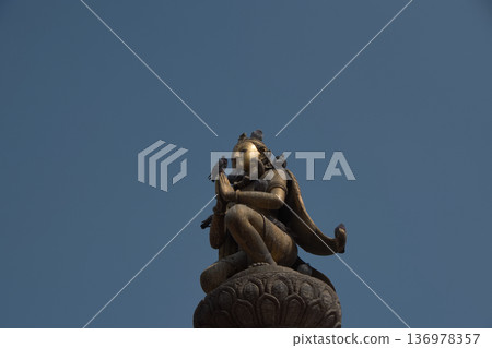 尼泊爾，一座金色的神像和鴿子雕像矗立在藍天下。 136978357