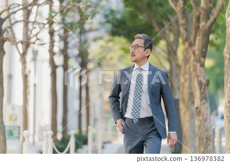 Businessman walking in town Businessman walking in town 136978382