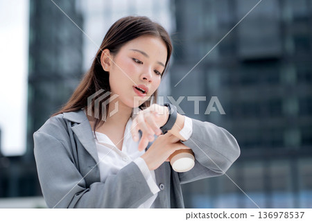 Young asian businesswoman in city talking to smartwatch using voice command with AI. 136978537