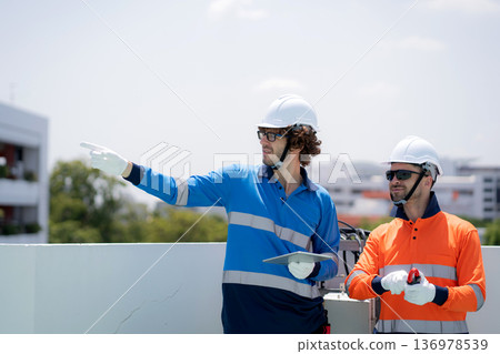 Team engineer inspect electrical control panel using tablet checking voltage. Team engineer inspect electrical control panel using tablet checking voltage. 136978539