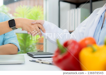 Happy man patient handshake with doctor nutritionist after success medical consulting diagnosis. Happy man patient handshake with doctor nutritionist after success medical consulting diagnosis. 136978543