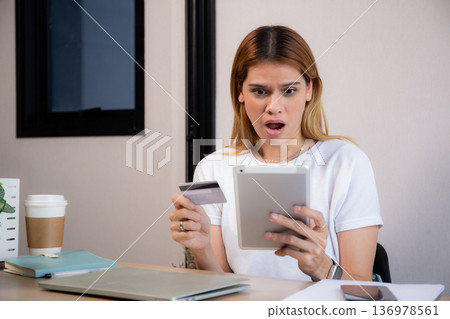Caucasian woman holding credit card or debit card paying with shopping online while looking tablet. Caucasian woman holding credit card or debit card paying with shopping online while looking tablet. 136978561