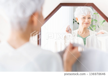 Senior woman choosing clothes in front of a mirror Senior woman choosing clothes in front of a mirror 136978646