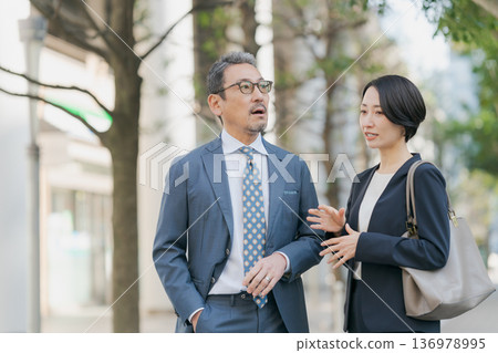 身著西裝的男女邊走邊聊 136978995