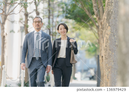 Men and women in suits walking through an office district Men and women in suits walking through an office district 136979429