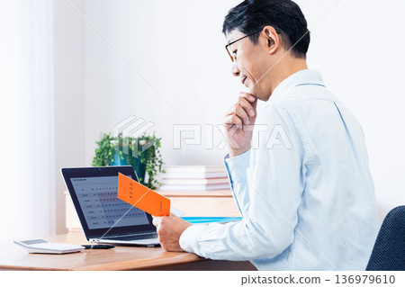 A middle-aged man thinking while looking at his pension book 136979610
