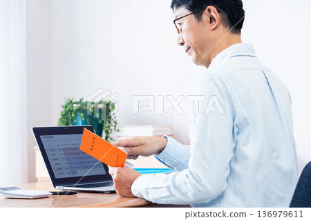 A middle-aged man thinking while looking at his pension book A middle-aged man thinking while looking at his pension book 136979611