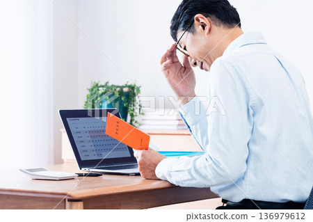 A middle-aged man thinking while looking at his pension book A middle-aged man thinking while looking at his pension book 136979612