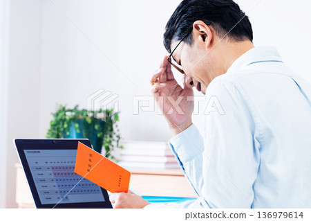 A middle-aged man thinking while looking at his pension book A middle-aged man thinking while looking at his pension book 136979614