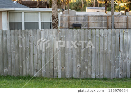 Wooden picket fence on green lawn surrounding property grounds for backyard protection and privacy 136979634